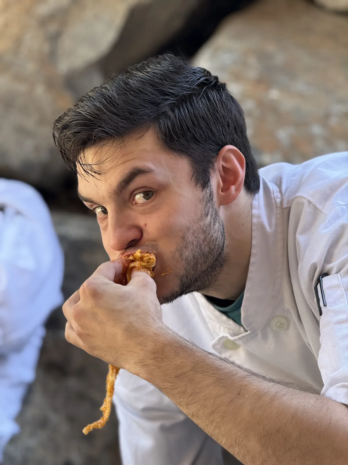 A Vacanza Romana cook stealing a bite of saucy pasta between shifts