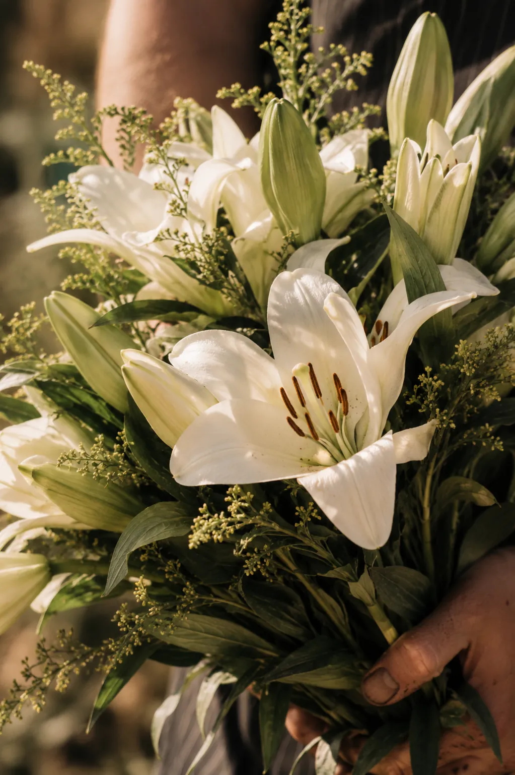 Chef Devin Dedier in a striped apron holding a bouquet of white lilies on Mother's Day at Vacanza Romana