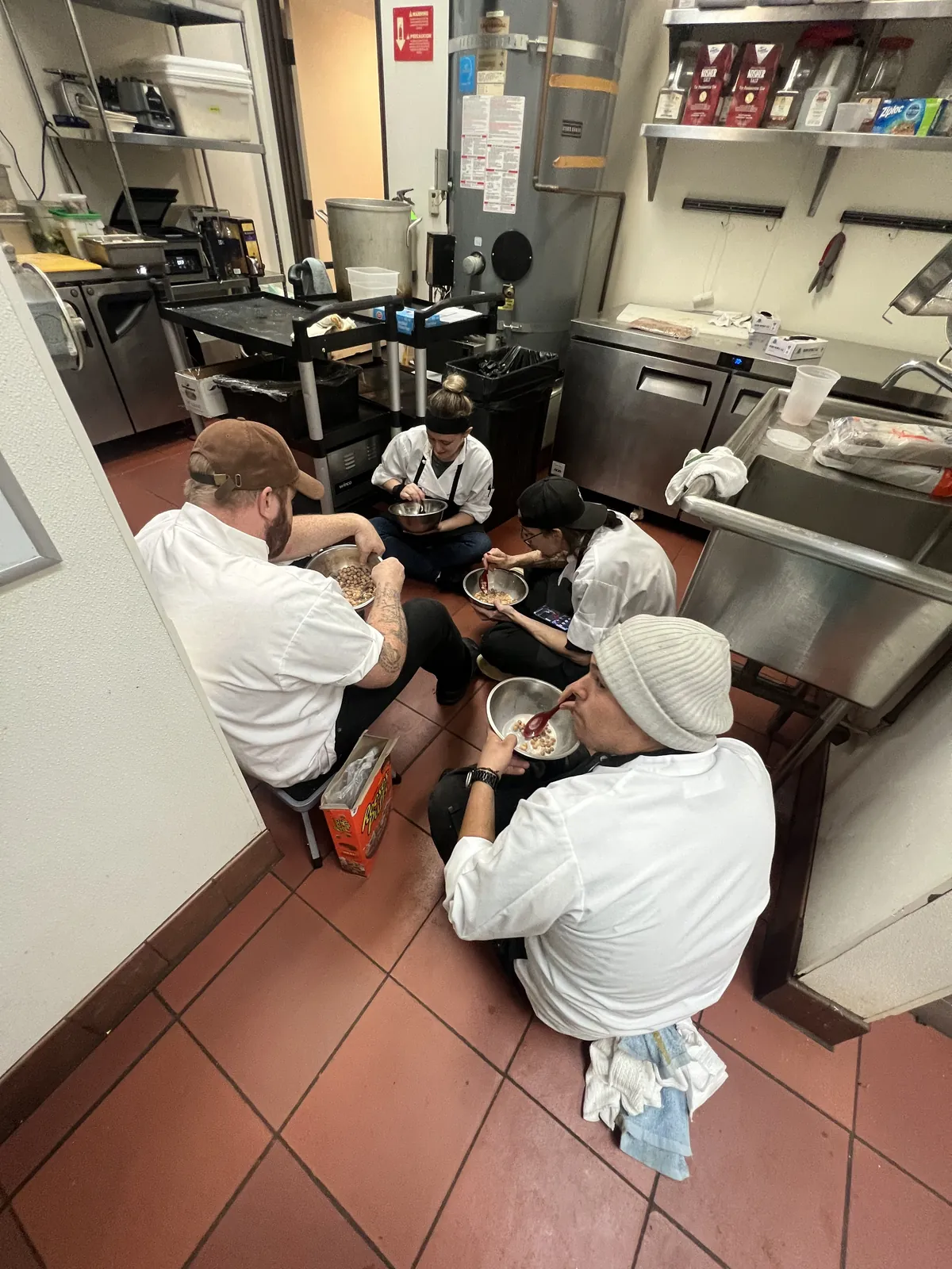 The Vacanza Romana kitchen crew on a break together, eating from steel bowls on the kitchen floor